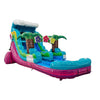 Large tropical-themed inflatable water slide featuring a single blue sliding lane, palm tree decorations, colorful flower accents, and an extended splash pool with vibrant blue and pink base in indoor warehouse setting.