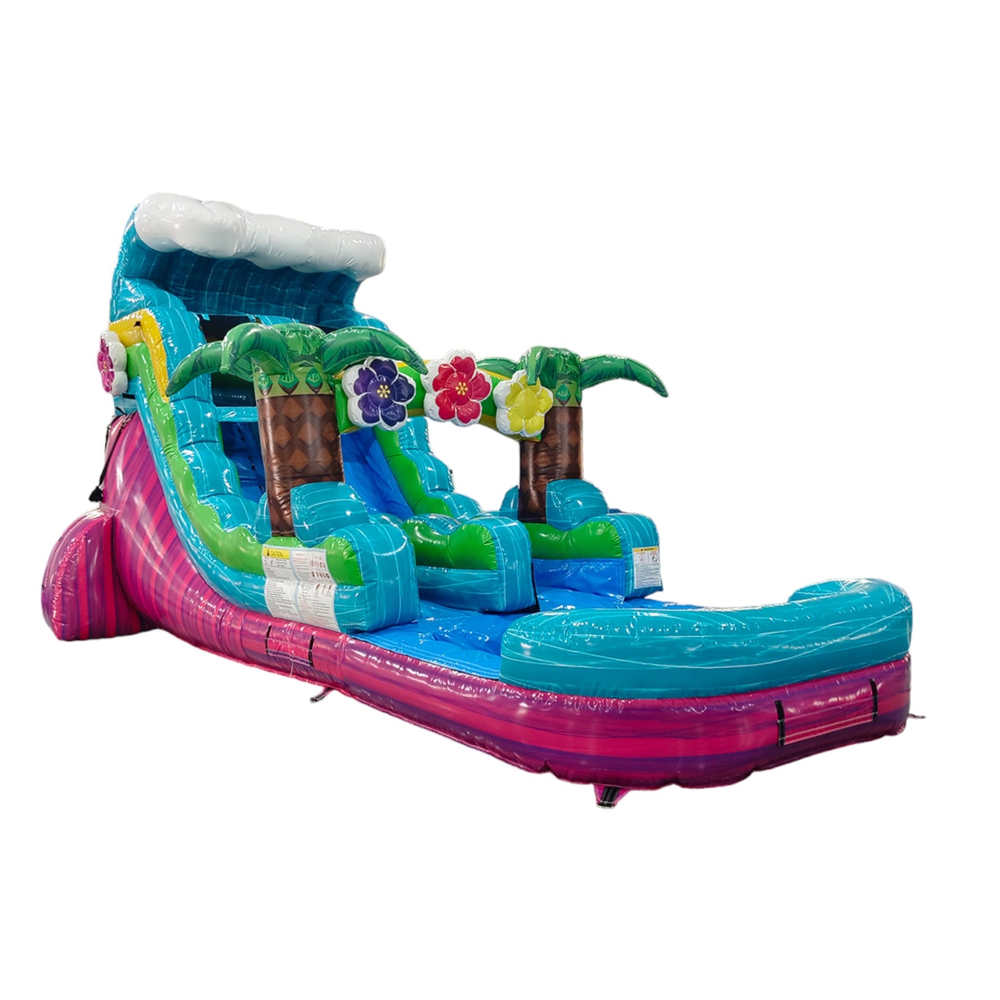 Large tropical-themed inflatable water slide featuring a single blue sliding lane, palm tree decorations, colorful flower accents, and an extended splash pool with vibrant blue and pink base in indoor warehouse setting.