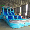 Close-up view of the 15ft Bahama Blast water slide displaying details of the blue sliding lanes, central climbing section, inflatable palm trees, and wave-patterned splash pool in an indoor facility.