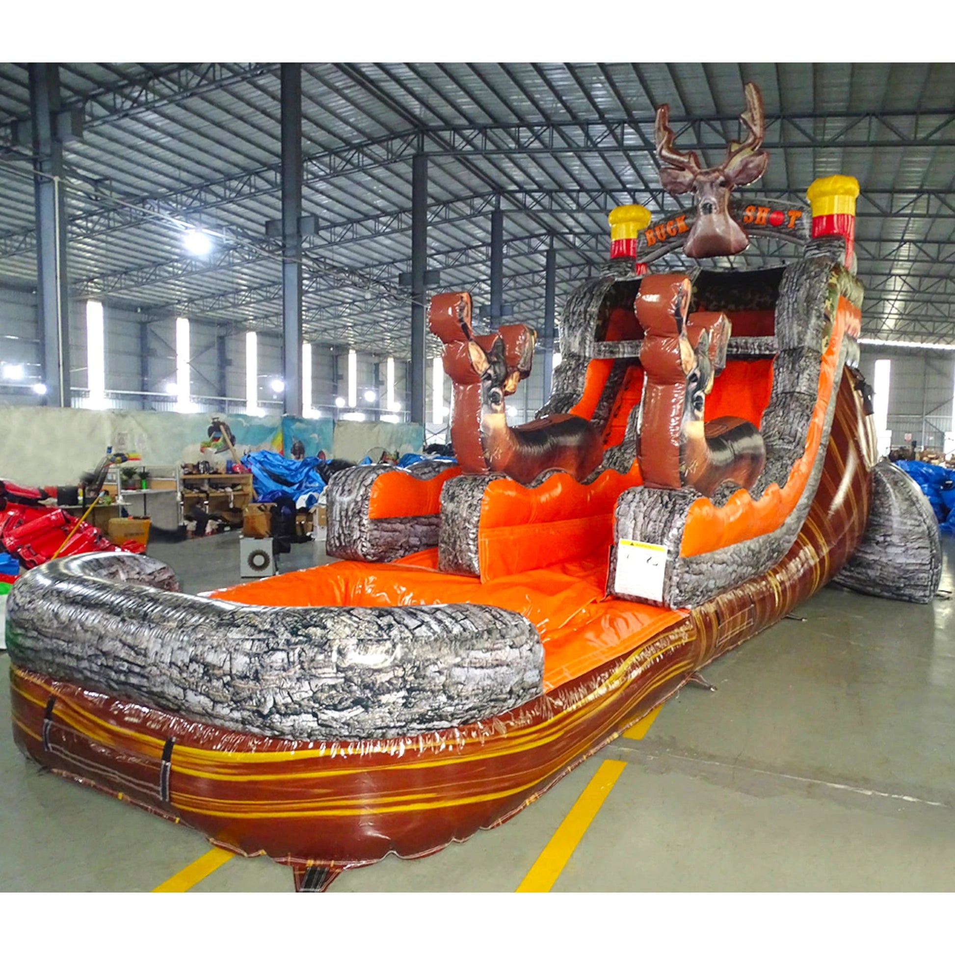 Side view of Buck Shot inflatable water slide displaying full length with orange sliding lane, tree bark-textured supports, and large splash area with wood-grain pattern.