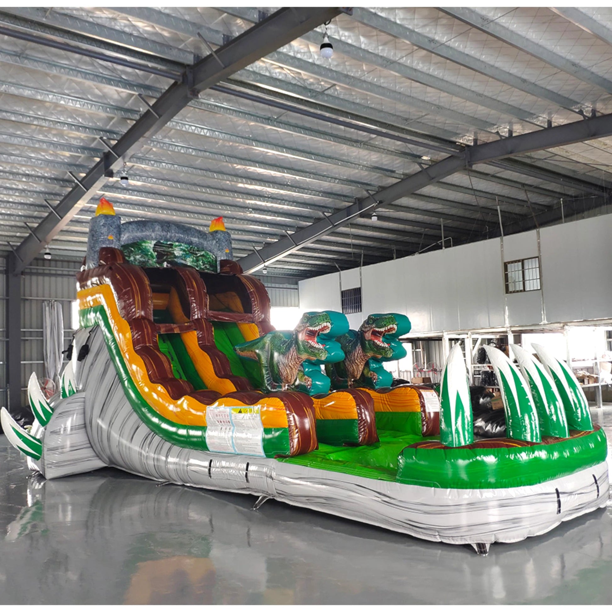 Close-up side view of Dino Dive single lane water slide showcasing dinosaur decorations, brown sliding surface, green accents, and white inflatable base.