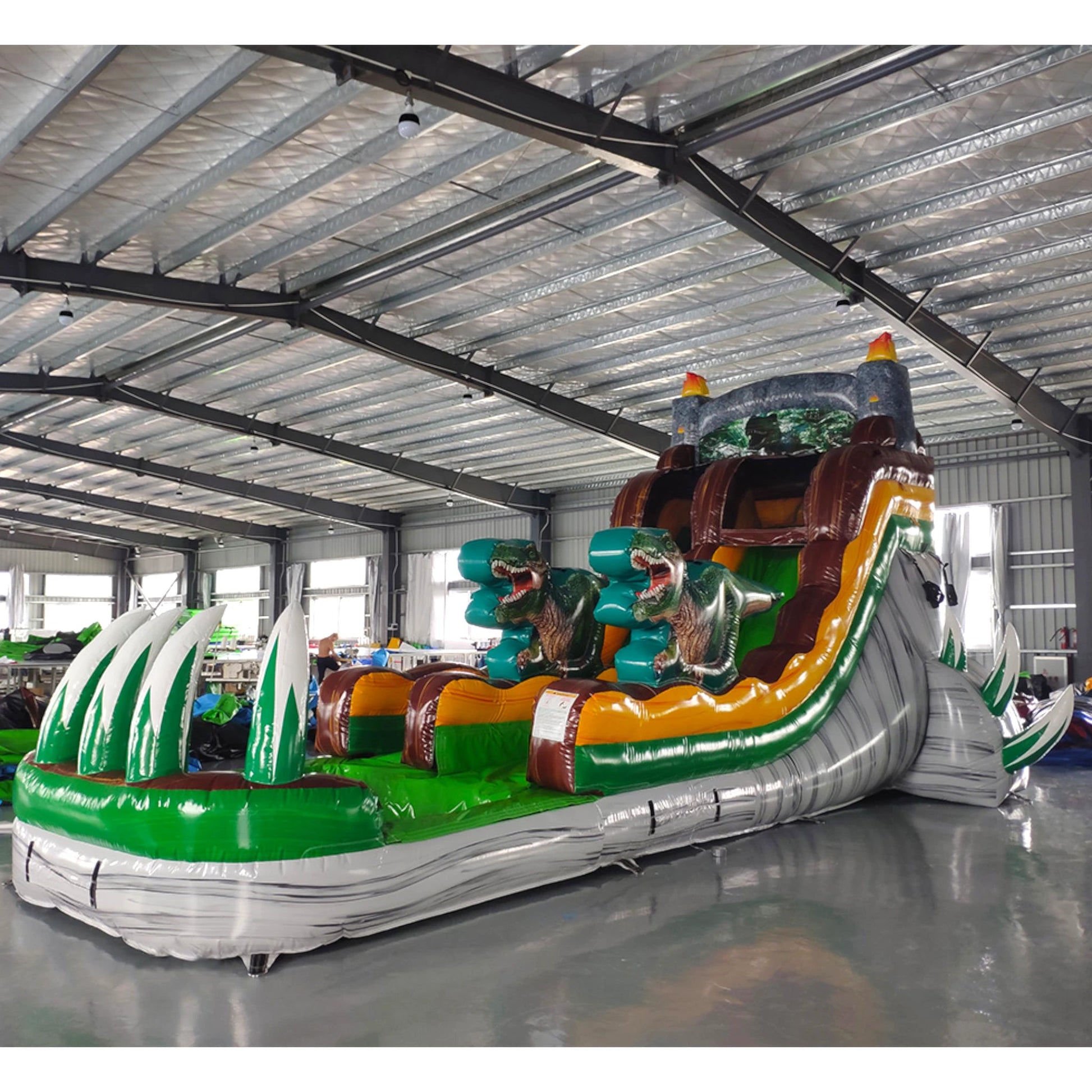 Side view of Dino Dive inflatable water slide displaying full length with dinosaur figures, single sliding lane, and green splash pool area in indoor facility.