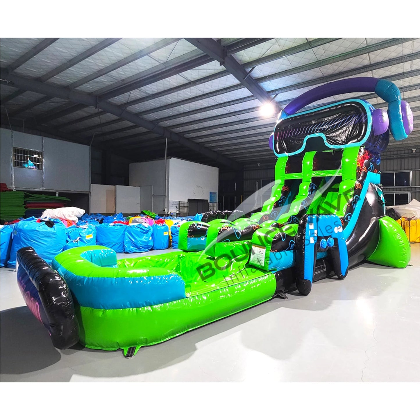 Large gaming-themed inflatable water slide featuring a single green sliding lane, VR headset design on top, and an extended splash pool with "Game On" sign in indoor warehouse setting.