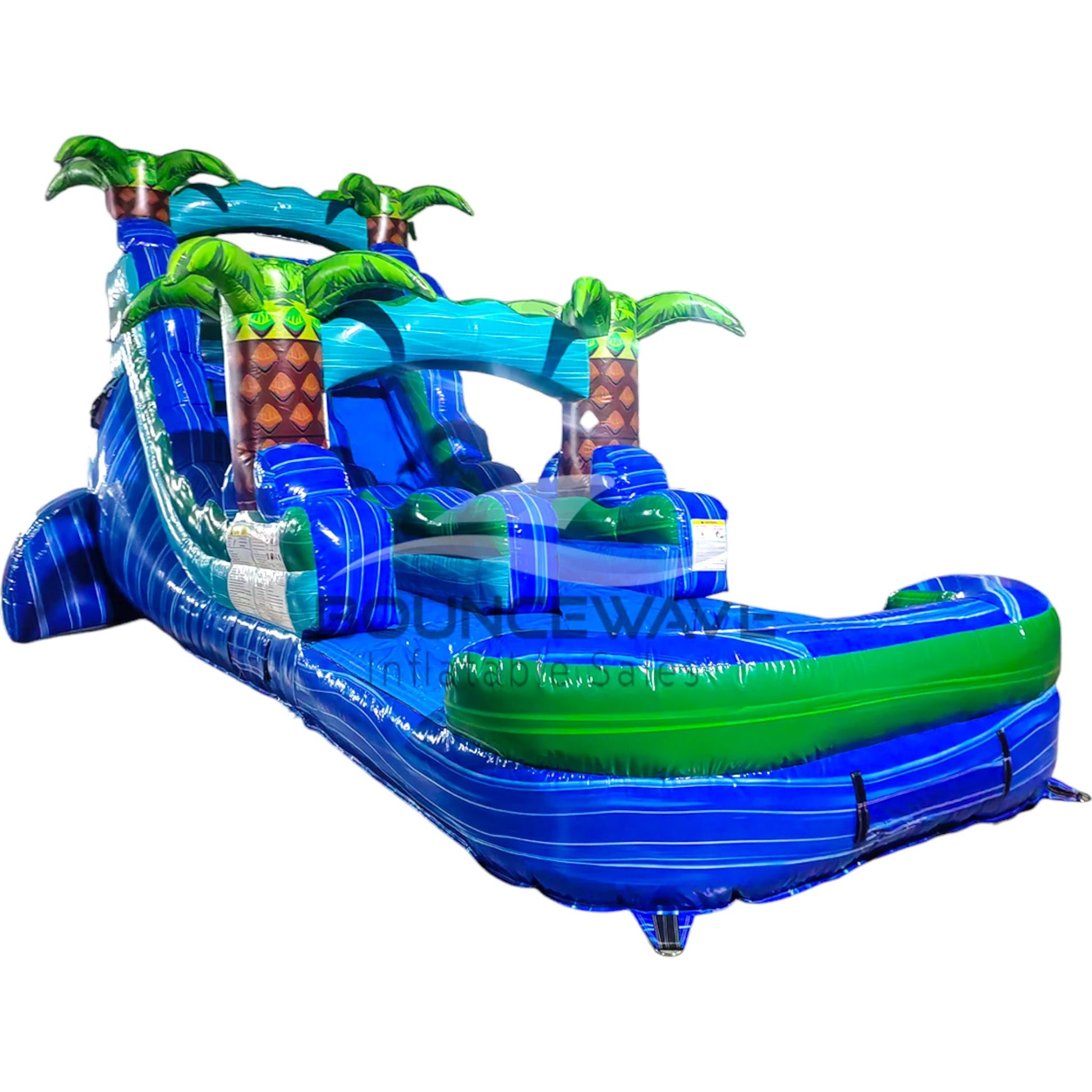 Large tropical-themed inflatable water slide featuring a single blue sliding lane, palm tree decorations, and an extended splash pool with wave-like design.