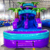 Front view of Purple Plunge single lane water slide in indoor warehouse, showing tall structure with purple sliding surface, palm trees, and large splash area with blue accents.