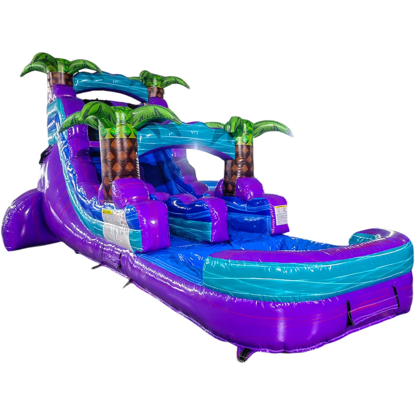 Large tropical-themed inflatable water slide featuring a single purple sliding lane, palm tree decorations, and an extended splash pool with vibrant blue and purple colors.