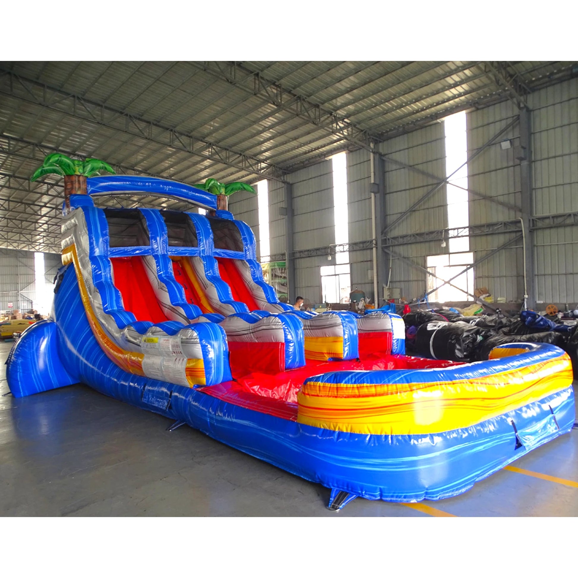 15ft Rip Curl Dual Lane Center Climb Inflatable Water Slide side view showcasing blue frame, dual red slides, inflatable palm trees, and yellow-red pool area
