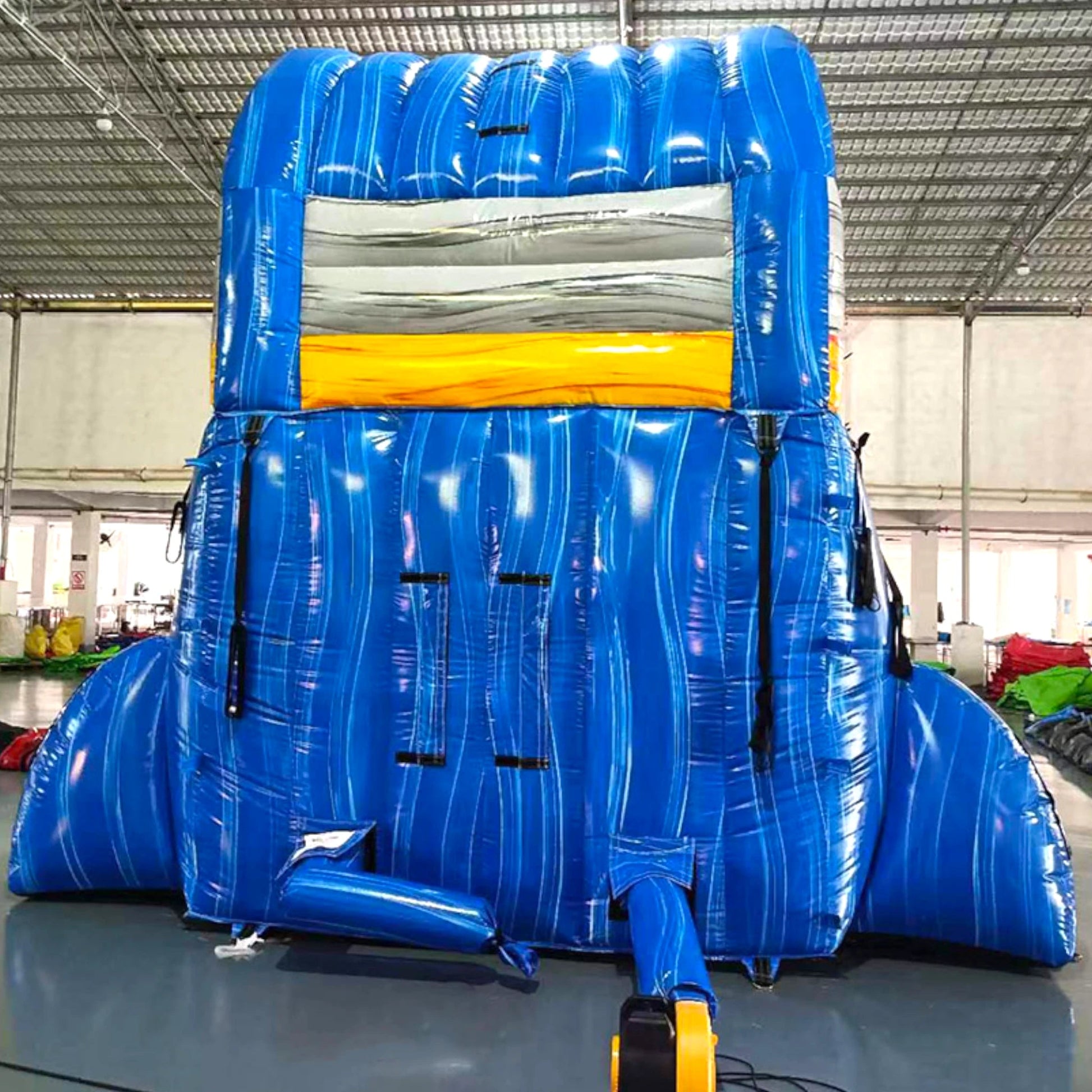 Rear view of Rip Curl single lane water slide in indoor warehouse, showing tall blue structure with climbing area and safety features.