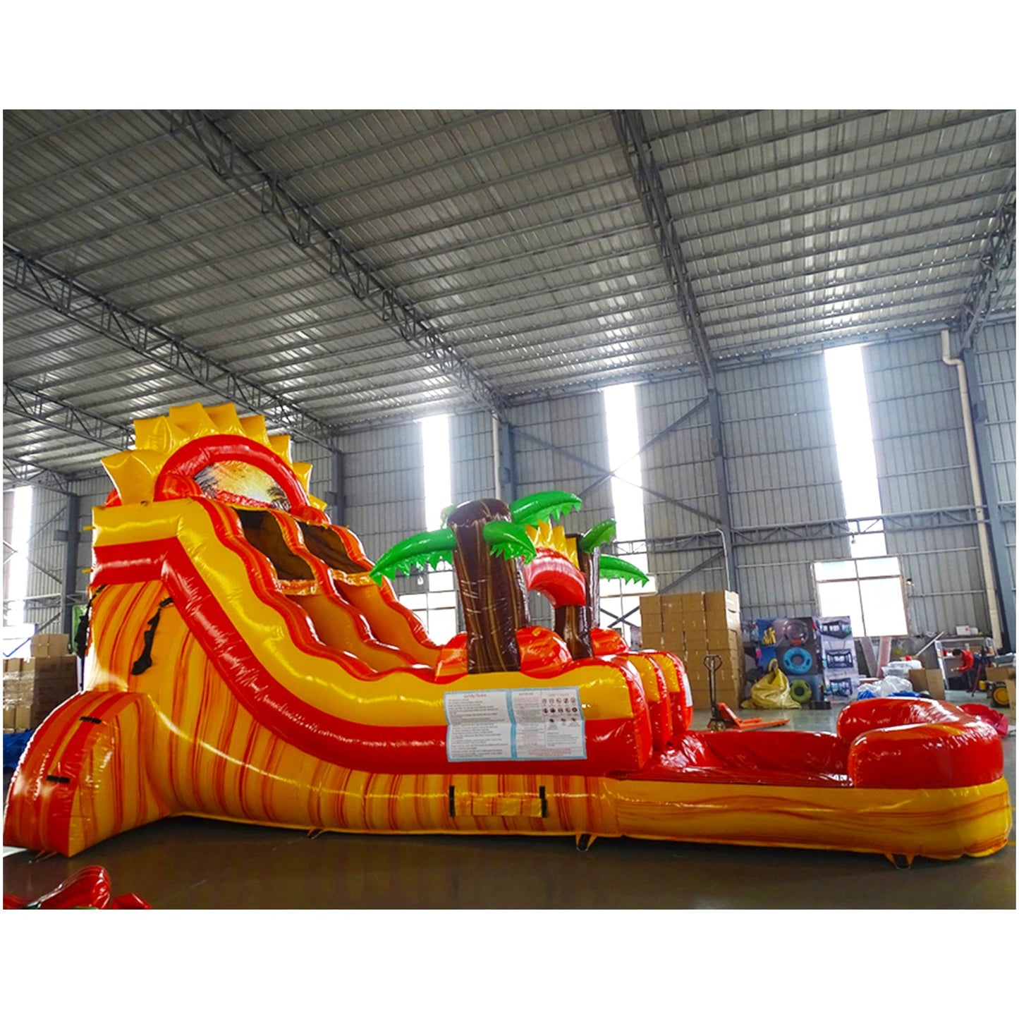  Inflatable tropical-themed water slide with yellow and red curves, palm tree decorations, and a single lane, set up in a large indoor warehouse