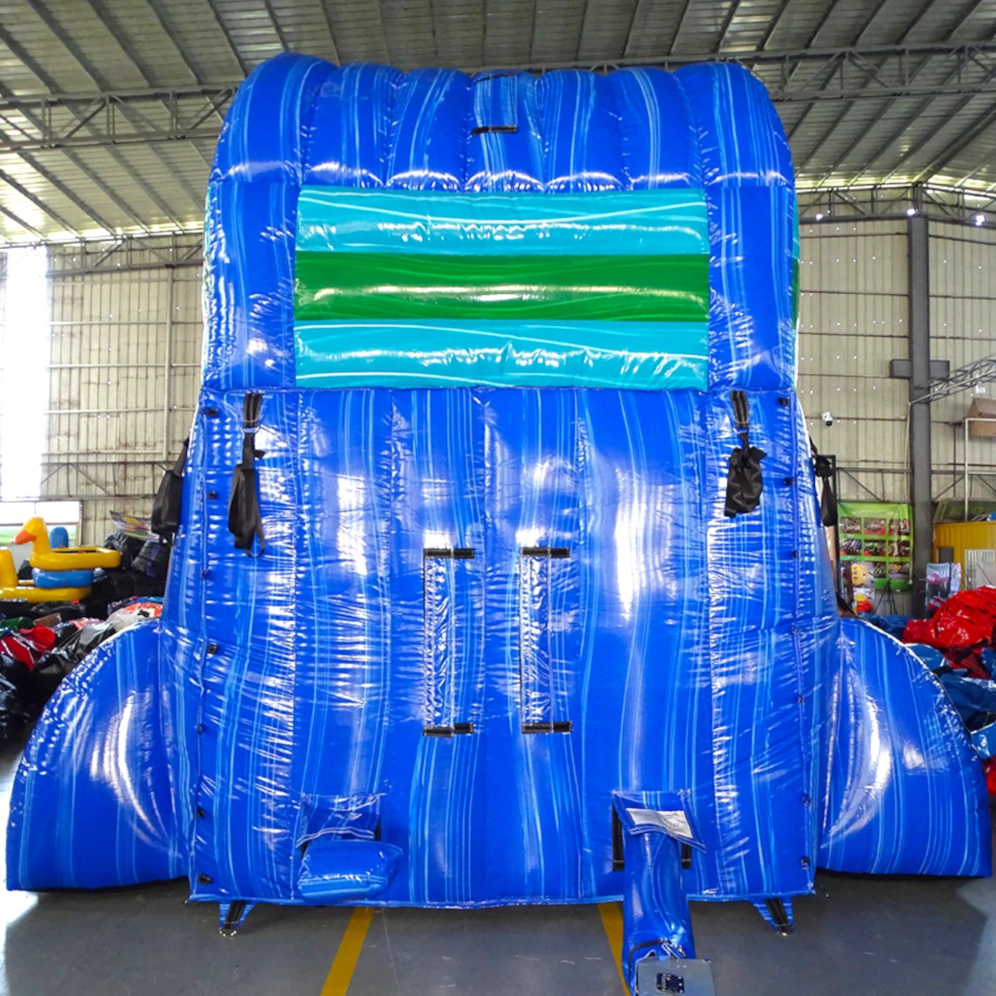 Rear view of Trop Wave single lane water slide, showcasing tall blue structure with climbing area, safety features, and tropical-themed top section with blue and green accents.