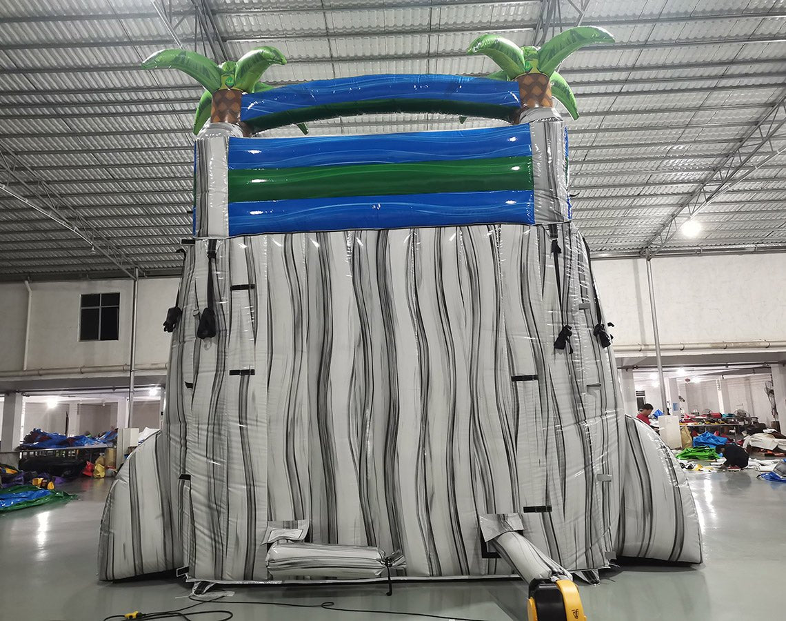 Rear view of 18ft Aloha Splash Center Climb water slide showing white support structure, blue and green top section with palm tree decorations, and safety netting for the climbing area.