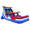 Side view of 18ft Baja Splash inflatable water slide featuring three blue lanes, tropical palm tree decorations, rainbow-colored arches, and a large red and blue splash pool area in an indoor warehouse setting.