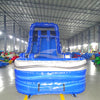 Front view of the 18-foot Blue Lagoon inflatable waterslide in an indoor setting, displaying its towering blue structure, dual sliding lanes, and large white and blue splash pool with wave-inspired graphics