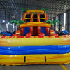 Front view of large inflatable water slide with tropical theme, featuring three red and yellow sliding lanes, palm tree decorations, and a central climbing structure, set up in an indoor warehouse.