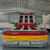 Front view of 18ft Fire Island inflatable water slide featuring red, yellow, and gray color scheme, three sliding lanes, inflatable palm trees, and a central climbing area, displayed in a large indoor warehouse.