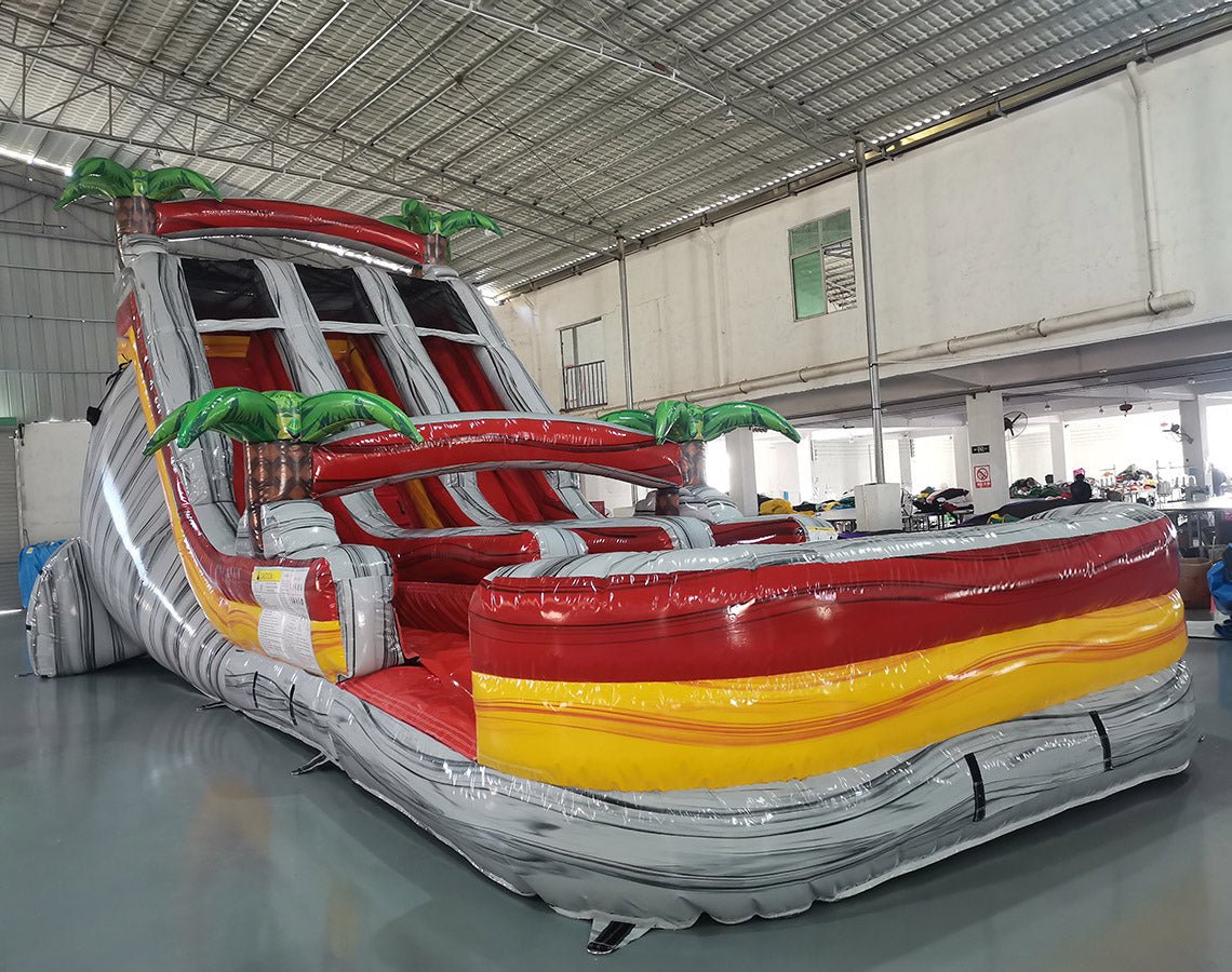 Angled view of the 18ft Fire Island Center Climb water slide, showcasing its three sliding lanes, central climbing structure, palm tree decorations, and large splash pool area, set up in a spacious indoor facility with other equipment visible.