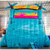 Rear view of tropical-themed inflatable water slide with palm tree decorations, showing tall blue structure and colorful top section in indoor warehouse setting.