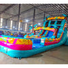 Side view of Island Flow Palms inflatable water slide showing full length with dual lanes, palm trees, and extended splash pool in warehouse environment.