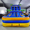 Front view of 18ft Lava Falls Center Climb water slide showing vibrant blue and yellow color scheme, three sliding lanes, inflatable palm trees, and a large splash pool area, displayed in a spacious indoor facility with other equipment visible.