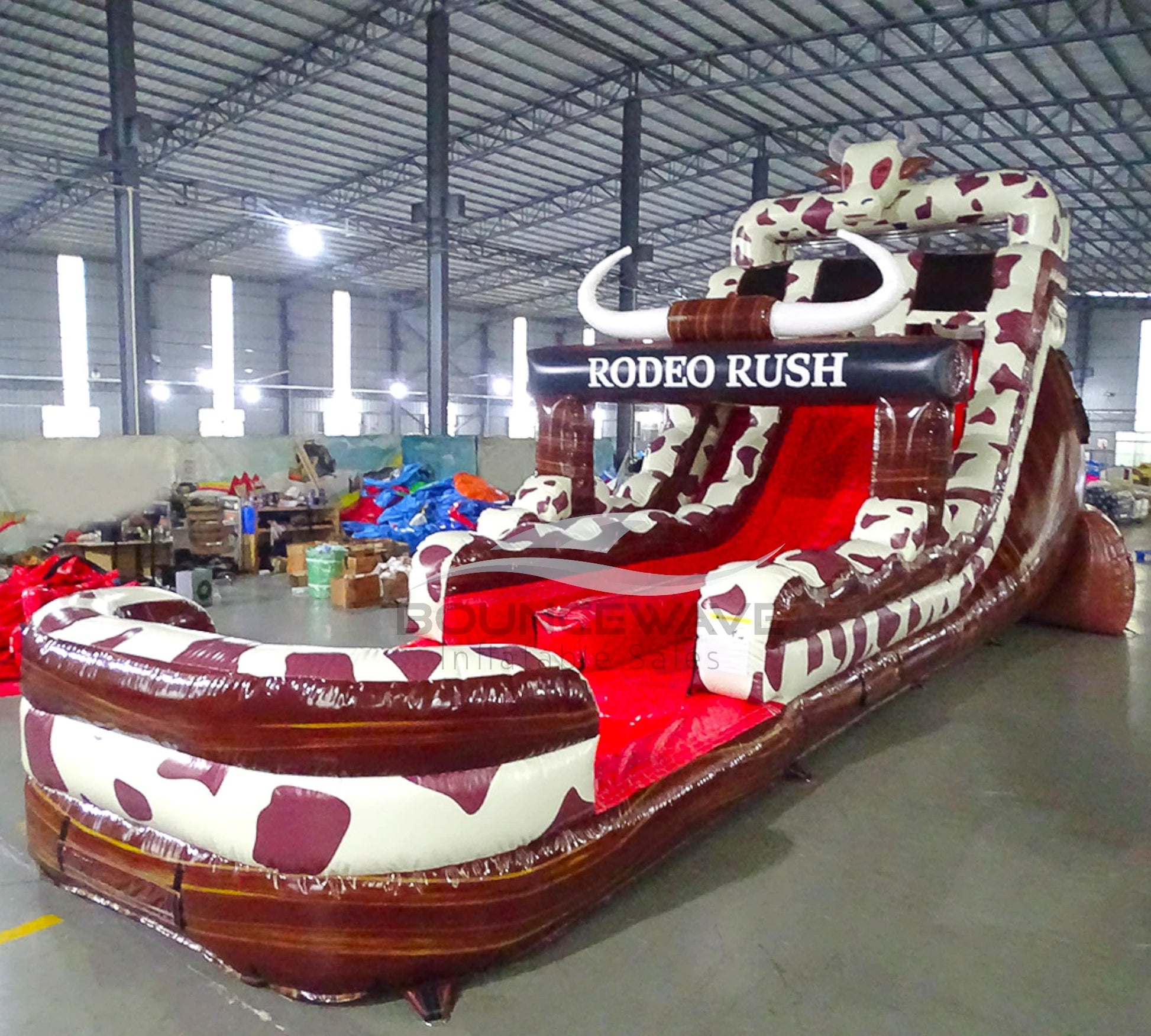 Close-up angle view of Rodeo Rush hybrid water slide, showcasing cow print theme, Rodeo Rush banner, red sliding lanes, and large splash pool with safety features.