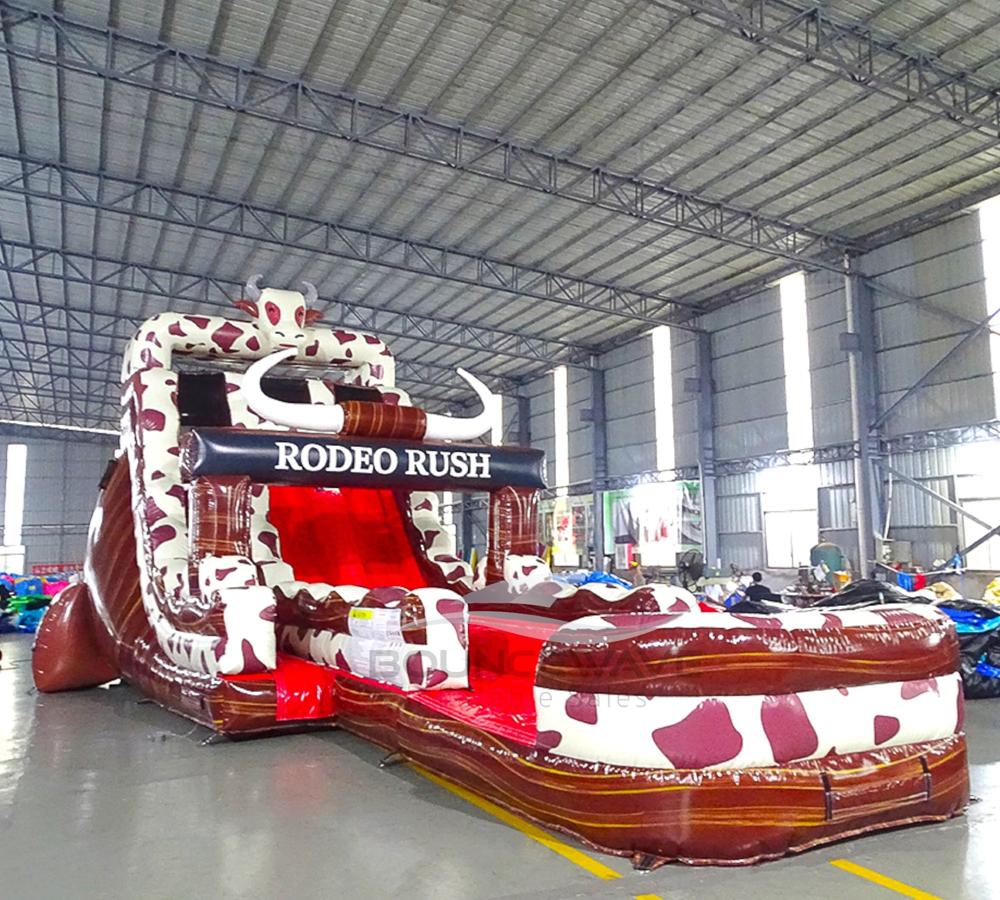 Side view of Rodeo Rush hybrid water slide showing full length with dual sliding lanes, cow print decorations, and large splash area with red sliding surface.