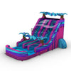 Side view of the 18ft Supernova Splash water slide showcasing its bright blue, pink, and purple color scheme. The slide features inflatable palm trees, three sliding lanes, and a large splash pool with wave-like patterns.