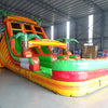 Side view of 18ft Tropical Inferno Center Climb water slide showing vibrant orange, green, and yellow colors, inflatable palm trees, and a large multi-colored splash pool area. The slide is displayed in an indoor facility with concrete flooring.