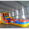 Rear view of 20ft Fiesta Fire Hybrid DL water slide featuring red and yellow colors, inflatable palm trees, and enclosed tube slide sections. The slide is set up in an indoor facility with metal roofing and other inflatables visible in the background.