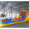 Side angle view of the 20ft Fiesta Fire Hybrid DL inflatable water slide, showcasing its red and yellow color scheme, palm tree decorations, and spacious splash pool. The slide combines open and tube slide elements, set up in an indoor warehouse with other equipment visible.