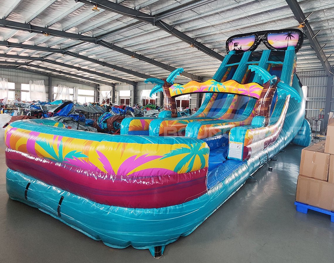 20ft Island Flow Dual Lane Center Climb Inflatable Water Slide side view showcasing vibrant colors, dual blue slides, inflatable palm trees, and extended splash pool
