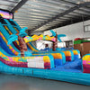 20ft Island Flow Dual Lane Center Climb Inflatable Water Slide featuring tropical theme, dual slides, sunglasses-shaped top, and palm tree decorations in warehouse setting
