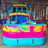 Large inflatable water slide with tropical theme, featuring turquoise sliding lanes, palm tree decorations, and a spacious splash pool area with colorful palm leaf designs. The slide has a "BOUNCEWAVE Inflatable Sales" logo and is set up in an indoor warehouse with metal roofing visible.