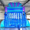 Side view of 20ft Mermaid's Cove Hybrid DL water slide showing vibrant blue, purple, and turquoise colors, shell-shaped design elements, and mermaid figures. The slide features both open and enclosed sliding sections, set up in an indoor facility with other inflatables visible in the background.