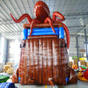 Rear view of 20ft Tentacle Typhoon Hybrid DL water slide showing red, brown, and blue design, with large octopus tentacles wrapping around the structure. The slide features both open and enclosed sliding sections, displayed in an indoor facility with other inflatables and equipment visible in the background.