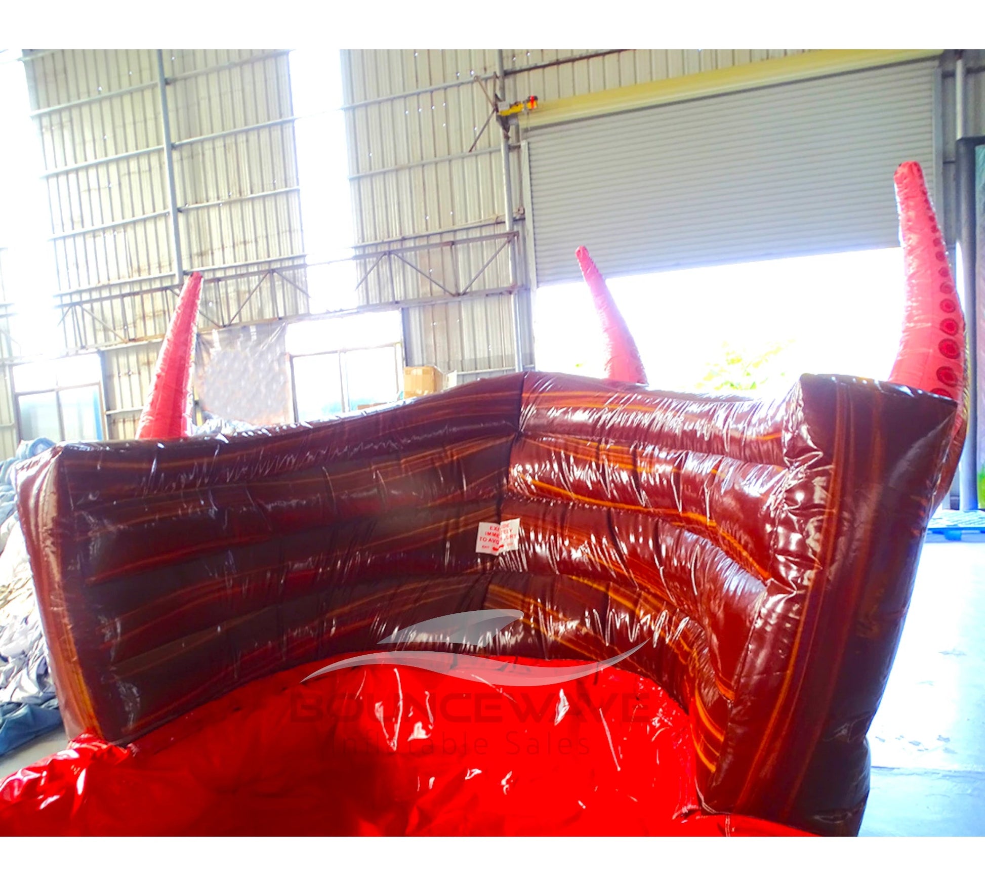 Large inflatable water slide with pirate ship theme, featuring red and brown colors, octopus tentacles, and a skull and crossbones flag. The slide has multiple lanes, a spacious splash pool area, and combines open and enclosed sections, set up in an indoor warehouse with metal roofing visible.