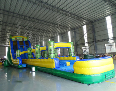 24ft Tiki Typhoon Dual Lane 2pc Commercial Water Slide with Inflatable Slip & Slide side view showcasing tiki-themed inflatable pillars, blue slides, and extended slip and slide
