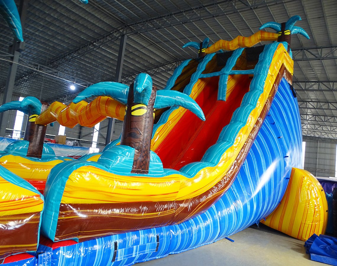 24ft Tropic Shock Dual Lane Commercial Water Slide with Inflatable Slip & Slide side angle displaying curved blue slides, tropical theme, and long water play area in indoor facility
