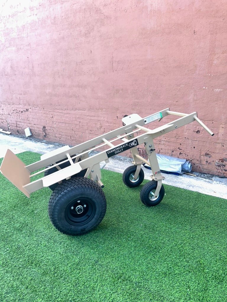 4-Wheel Heavy Duty Hand Truck Dolly with Brake featuring tan metal frame, large pneumatic tires, and brake mechanism for secure stopping on green turf
