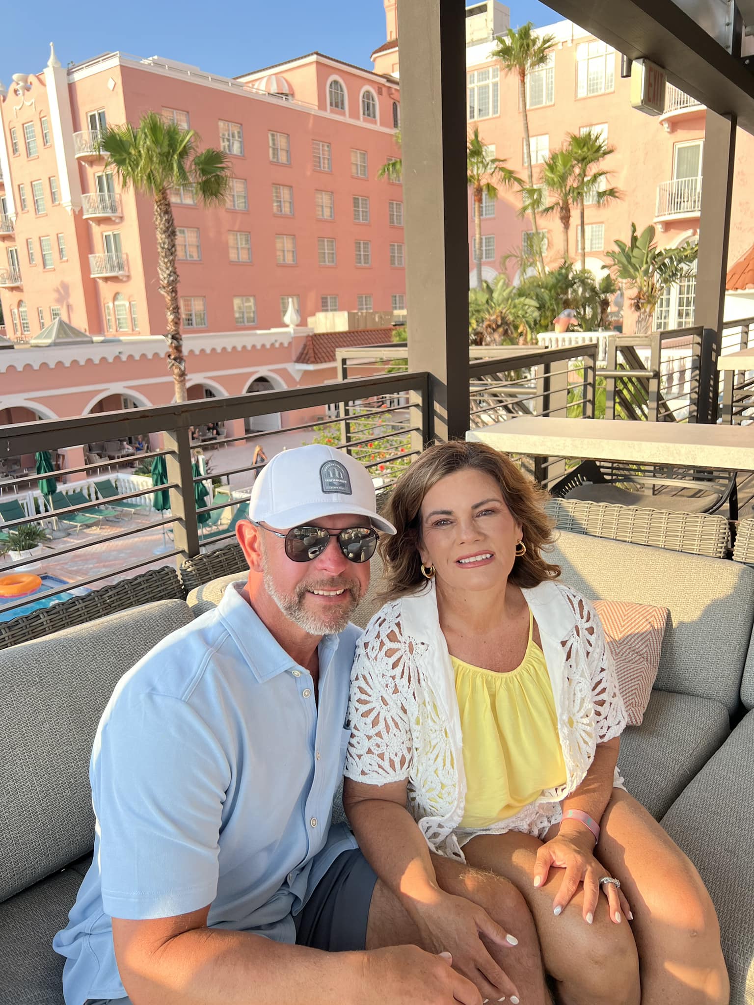 Jason & Kimberly Ladd, Founder & CEO, smiling together on a balcony overlooking colorful buildings and palm trees, showcasing a relaxed vacation atmosphere