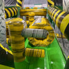 Interior view of 46ft Hazardous Commercial Hybrid Inflatable Obstacle Course showing various obstacles. The image displays yellow inflatable cylinders, a gray inflatable barrel, and yellow and black striped walls. Green flooring is visible, along with mesh netting on the sides for safety.