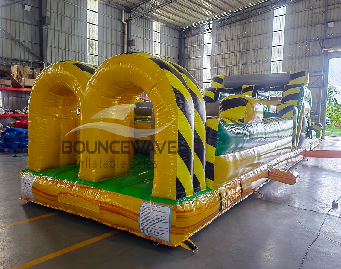 46ft Toxic Open Air Hybrid Inflatable Obstacle Course featuring yellow and black hazard stripes, multiple arches, and green base in warehouse setting
