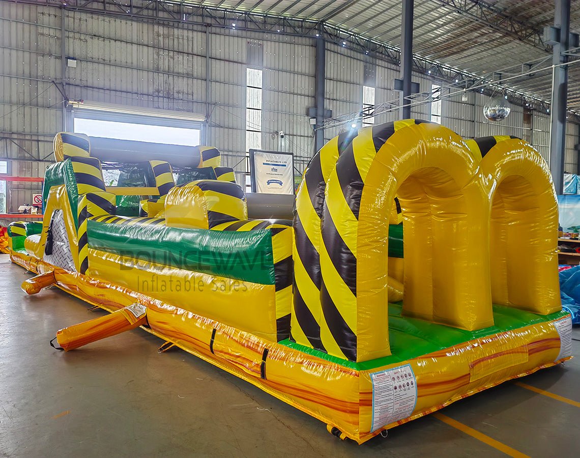 46ft Toxic Open Air Hybrid Inflatable Obstacle Course side view displaying long yellow structure with black hazard stripes, multiple challenges, and green base
