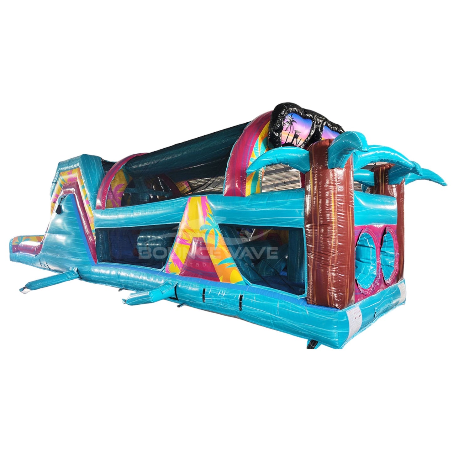 Side view of 53ft XL Island Flow Commercial Hybrid Inflatable Obstacle Course isolated on a white background. The inflatable showcases dual blue slides, brown inflatable palm tree trunks with blue leaves, and a long turquoise base with yellow and pink accents. Large sunglasses with a beach scene top the entrance, highlighting its tropical theme for commercial use.