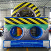 Rear view of 53ft XL Radioactive Run Commercial Hybrid Inflatable Obstacle Course showing the entrance area. Features a large yellow and black striped arch, dual circular entrances with blue trim, and a diamond plate pattern base. Safety instructions are visible on the front panel. Set in a warehouse with concrete flooring and various other inflatable products visible in the background.