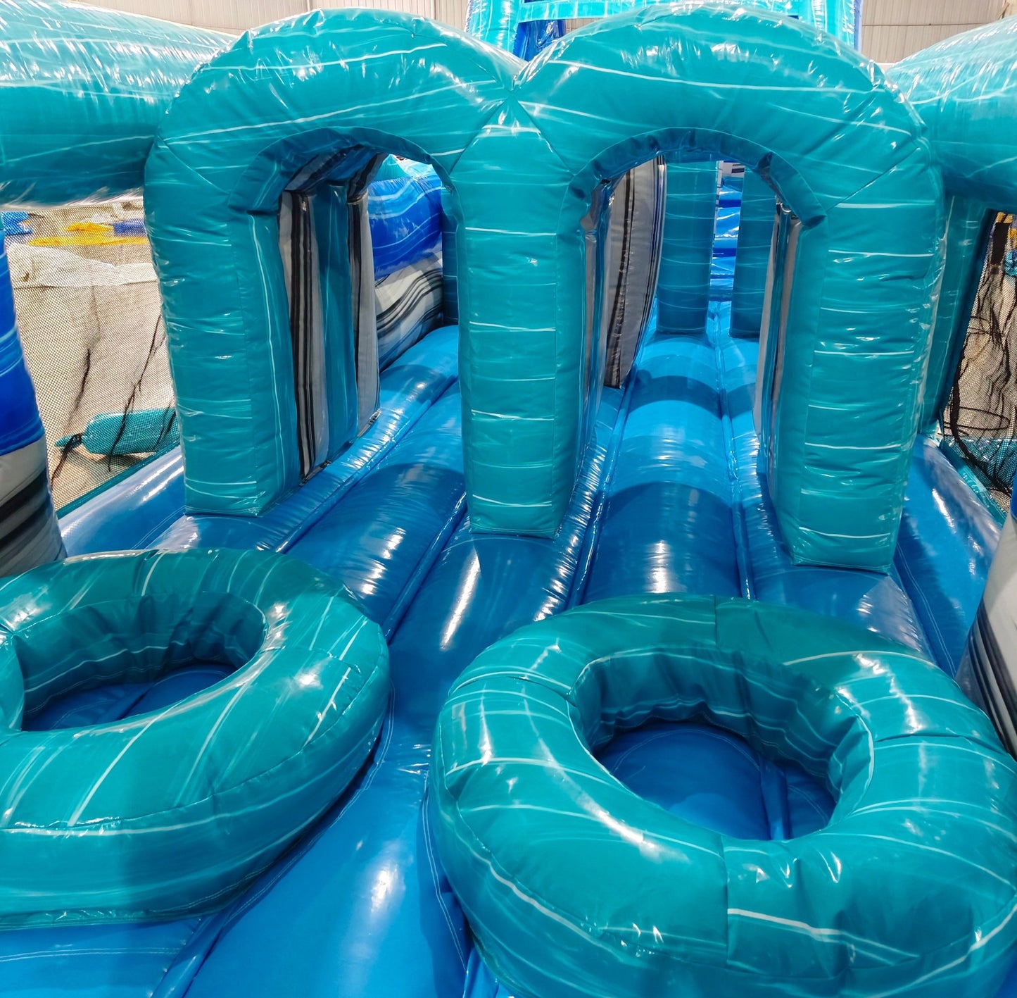 62ft Bahama 2-Piece Wet/Dry Inflatable Obstacle Course close-up of turquoise inflatable obstacles with arched openings and circular platforms
