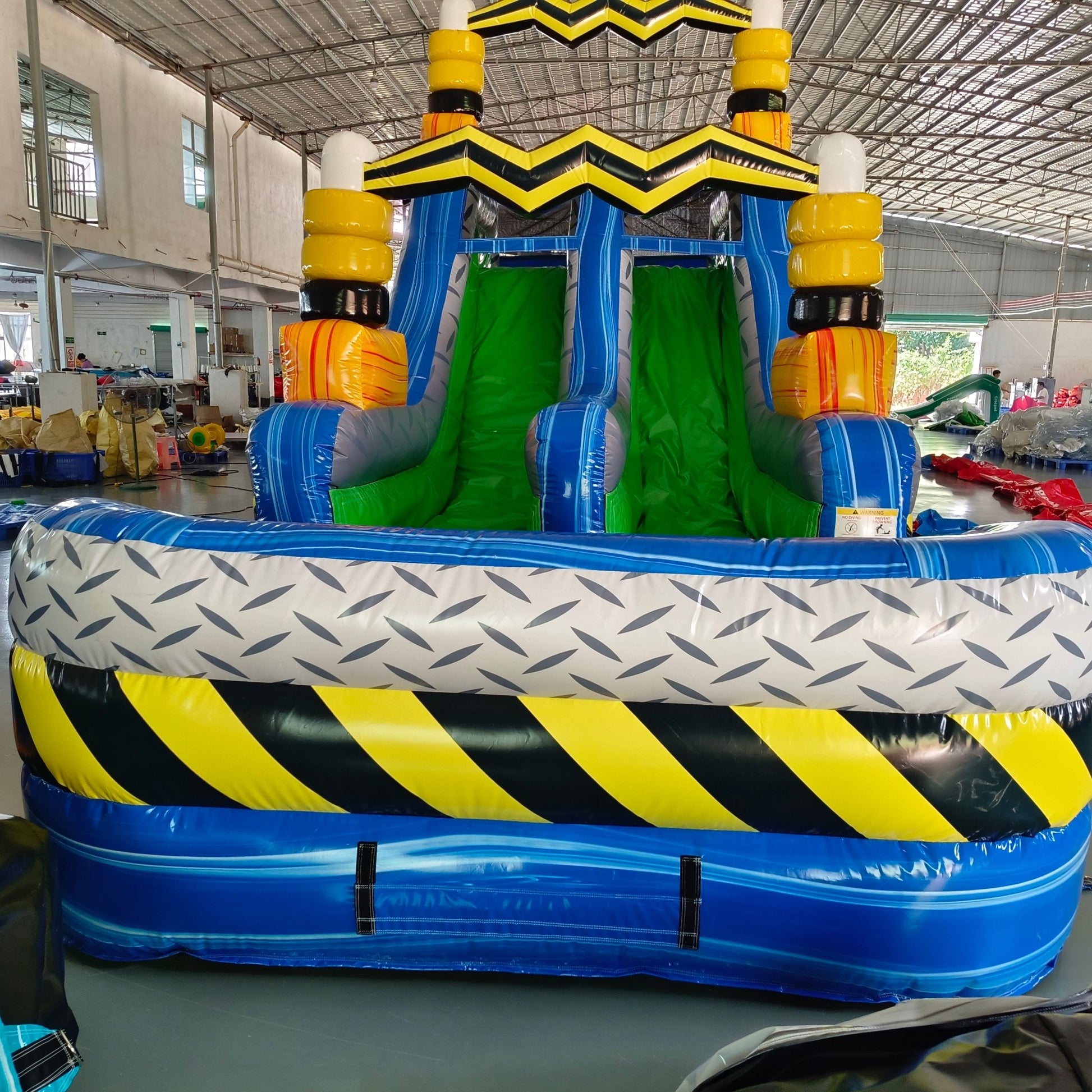 92ft Radioactive Run 3-Piece Wet/Dry Inflatable Obstacle Course side view displaying yellow and black caution-striped design, green slides, and blue inflatable base in indoor facility
