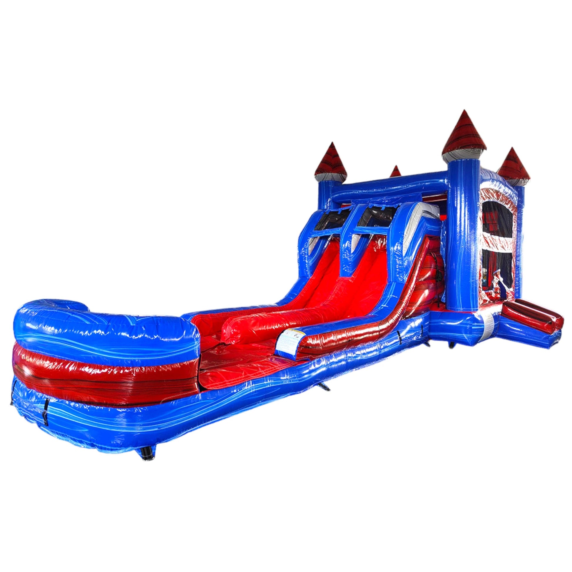 Large inflatable castle-themed combo featuring a bounce house with blue walls and red turrets, dual slides, and a spacious splash pool. The structure has multiple climbing areas, mesh windows, and safety netting. Set up in an indoor warehouse with metal roofing and other inflatable products visible in the background.