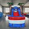 Front view of Baja Thunder Econo Combo, showcasing the bounce house entrance flanked by inflatable palm trees, with a red slide leading to a blue and white splash pool. Set up in an indoor facility with other inflatable products visible in the background.