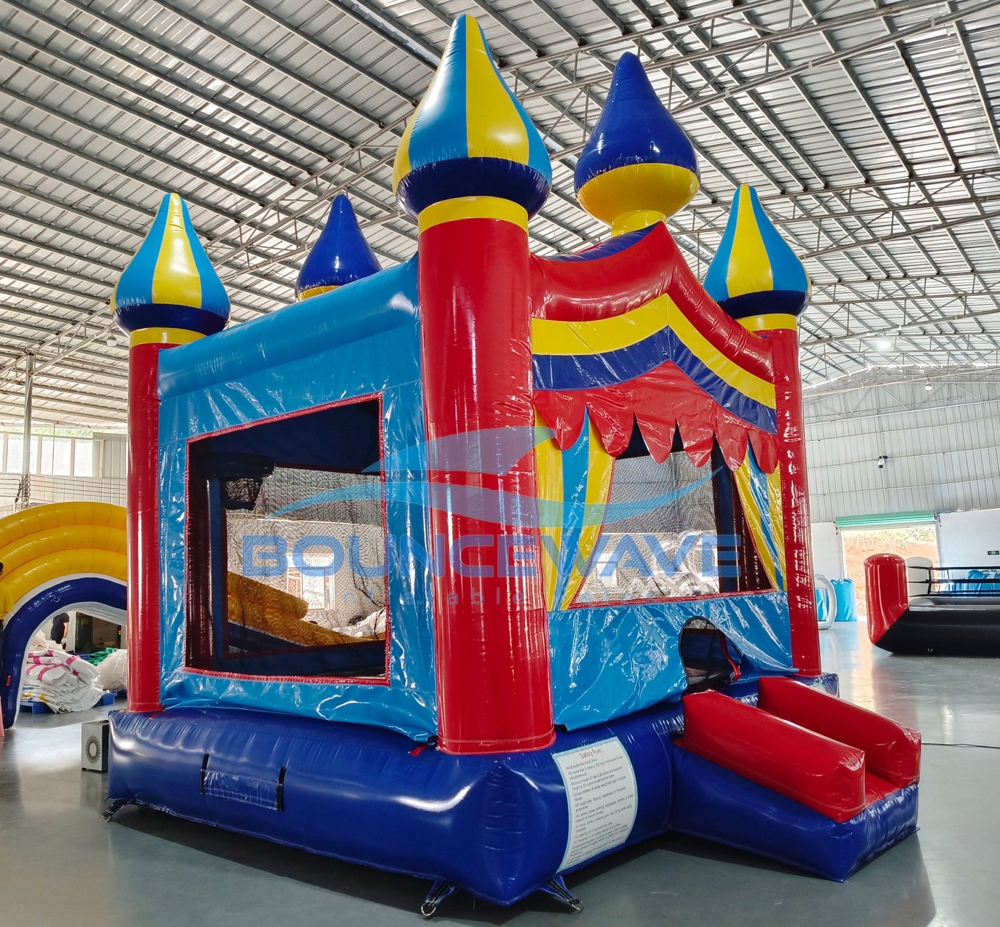 Carnival Commercial Grade Bounce House side angle view highlighting five spire tops, large entrance, and multicolored inflatable structure
