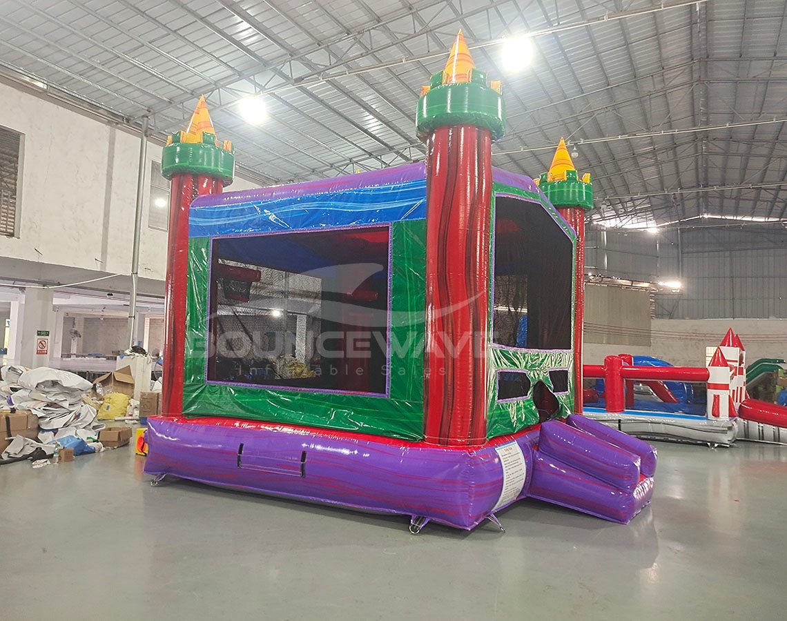 Euro Marble Commercial Grade Bounce House side angle displaying red towers with yellow tops, blue roof, and green walls in indoor facility
